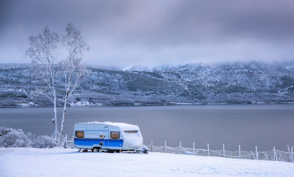 a caravan in the snow on the edge of a lake